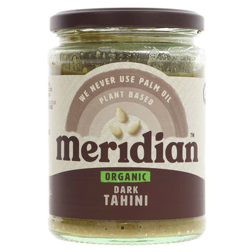 A glass jar of organic dark tahini with a metal lid