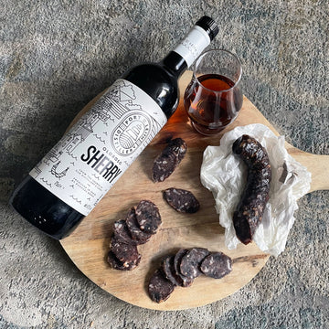 black garlic & oloroso sherry salami on a chopping board with sherry