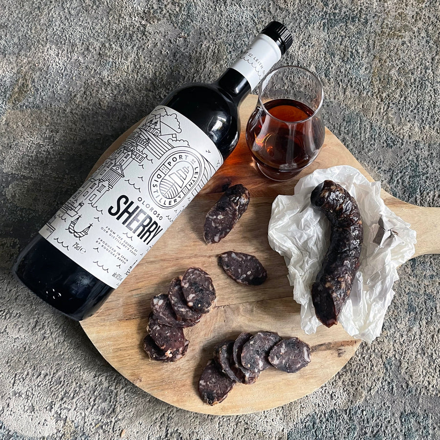 black garlic & oloroso sherry salami on a chopping board with sherry