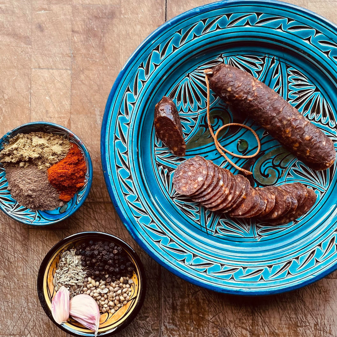 Beautiful plate of pork merguez salami. Vibrant blue plate with a variety of spices
